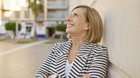 Photo for Caucasian senior woman smiling outdoors in an urban setting wearing stripes - Royalty Free Image