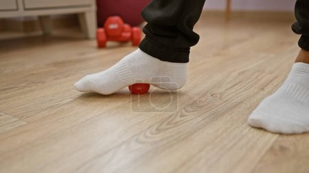 Man practicing foot exercise with red ball in rehabilitation clinic