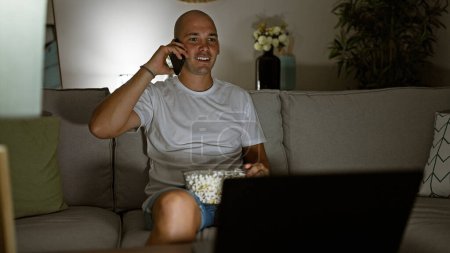 Téléchargez les photos : Jeune homme hispanique regardant un film parler sur smartphone souriant à la maison - en image libre de droit