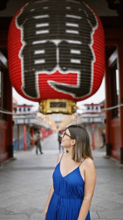 Schöne hispanische Frau mit Brille, fröhlichem Lächeln im Senso-ji-Tempel, eingetaucht in japanische Tradition, fröhlicher lateinischer Erwachsener, der die reiche Kultur Tokyos erkundet