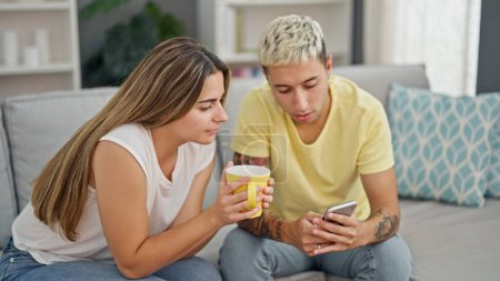 Téléchargez les photos : Beau couple utilisant smartphone boire du café à la maison - en image libre de droit
