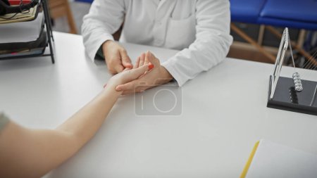 Photo for A doctor examines a patient's wrist in an indoor clinic setting, capturing a caring medical consultation moment. - Royalty Free Image