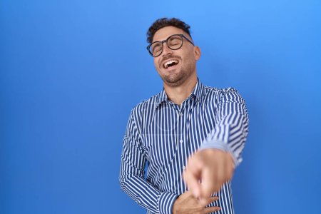 Photo for Hispanic man with beard wearing glasses laughing at you, pointing finger to the camera with hand over body, shame expression - Royalty Free Image