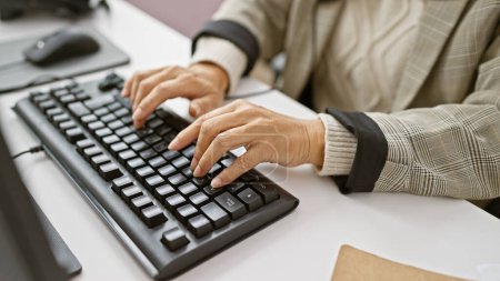 Reife Frau tippt im Büro auf einer Tastatur, was den Berufsalltag widerspiegelt.