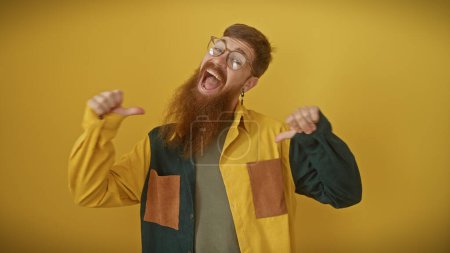 Téléchargez les photos : Bel homme rousse avec barbe pointant sur lui-même sur fond jaune isolé - en image libre de droit