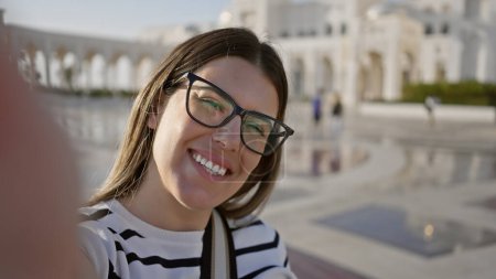 Young brunette woman enjoys tourism at qasr al watan palace in abu dhabi, showcasing happiness and culture.