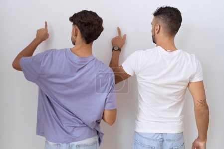 Foto de Homosexual gay pareja de pie sobre blanco fondo posando hacia atrás apuntando adelante con dedo mano - Imagen libre de derechos