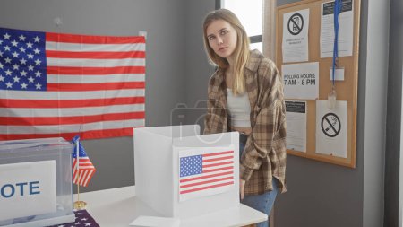 Eine junge kaukasische Frau steht nachdenklich mit einer amerikanischen Flagge in einem US-Wahlzentrum und verkörpert Demokratie und Bürgerpflicht.