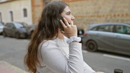 Spanisch Frau mit Smartphone auf der Straße der Stadt, mit Autos und Gebäuden im Hintergrund.