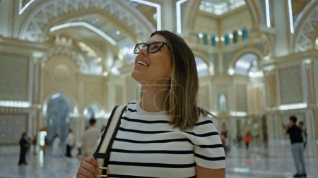 Photo for A smiling young adult woman enjoys sightseeing inside the luxurious qasr al watan palace in abu dhabi. - Royalty Free Image