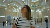 A smiling young adult woman enjoys sightseeing inside the luxurious qasr al watan palace in abu dhabi. Sweatshirt #710164442