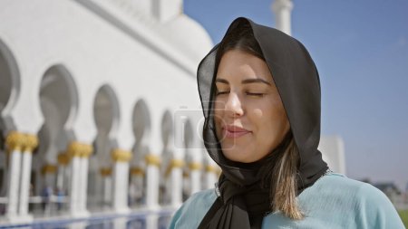 Photo for A serene young woman enjoys the peaceful ambiance of an islamic mosque in abu dhabi, uae. - Royalty Free Image