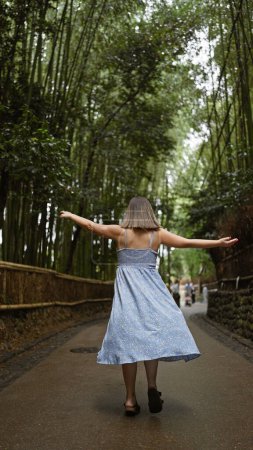Fröhliche hispanische Frau mit Brille dreht sich im Kreis, ihr schönes Kleid fließt in Kyotos bezauberndem Bambuswald