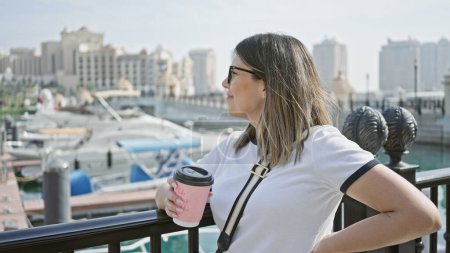 Adult hispanic woman enjoys coffee while overlooking a modern marina in doha, qatar. puzzle 710164746