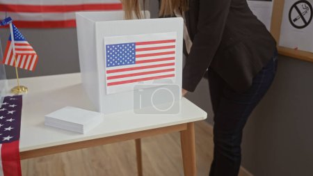 Téléchargez les photos : Une femme votant dans un stand électoral américain avec un drapeau américain derrière elle. - en image libre de droit