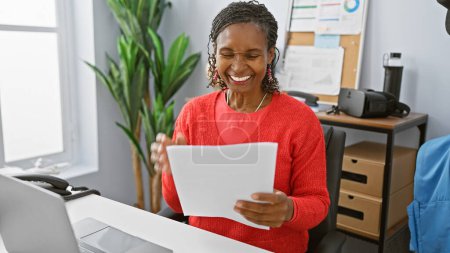 Reife afrikanisch-amerikanische Frau lacht, während sie ein Dokument in einem modernen Büro liest.