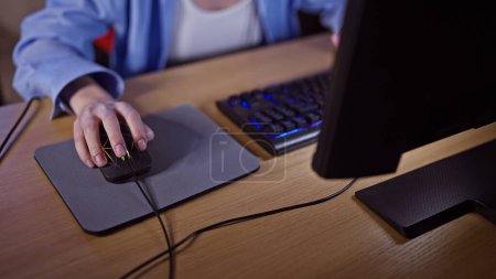 Foto de Primer plano de una mujer joven usando un ratón en una estación de ordenador oscura por la noche. - Imagen libre de derechos