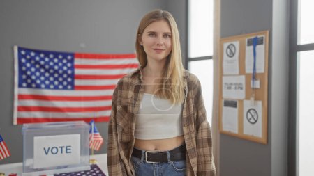 A young blonde woman stands confidently in a usa voting center adorned with flags and informational posters.