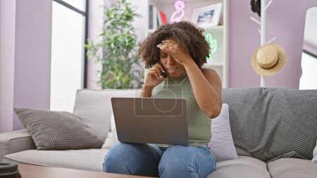 Mujer afroamericana estresada con trenzas usando laptop en casa