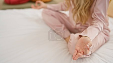 Photo for A young blonde woman meditates in a serene bedroom, promoting wellness and mindfulness. - Royalty Free Image
