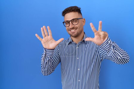 Foto de Hombre hispano con barba con gafas mostrando y señalando con los dedos número ocho mientras sonríe confiado y feliz. - Imagen libre de derechos