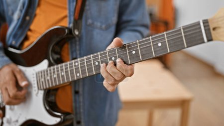 Photo for Close-up of a man playing guitar indoors, focusing on hand and strings for a musical concept. - Royalty Free Image