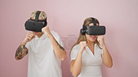 Photo for Beautiful couple playing boxing video game using virtual reality glasses over isolated pink background - Royalty Free Image