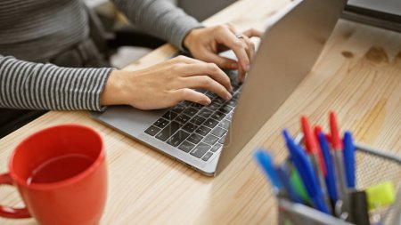 Téléchargez les photos : Femme blanche travaillant sur ordinateur portable dans un bureau moderne entouré d'accessoires de travail, illustrant l'environnement professionnel et productif. - en image libre de droit