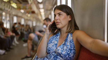Portrait of a beautiful young hispanic woman sitting alone inside a city's empty subway, engrossed in an urban social communication using her smartphone, speaking and calling in public transport