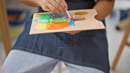 Téléchargez les photos : Un homme mélange de la peinture sur une palette dans un atelier d'art, évoquant créativité et apprentissage. - en image libre de droit