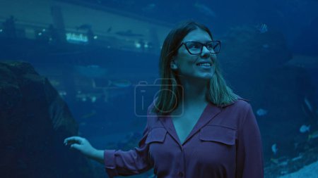 Foto de Una morena sonriente admirando la vida marina en el gran acuario submarino de dubai - Imagen libre de derechos