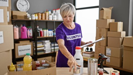 Mature woman volunteering at a donation center, organizing supplies in a warehouse.