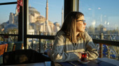A contemplative woman enjoys tea in a restaurant with a view of hagia sophia in istanbul at sunset. Stickers #710166498