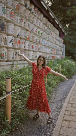 Photo for Beautiful hispanic woman smiling, standing by shake barrels at meiji temple while embracing japanese culture, all while donning glasses - Royalty Free Image