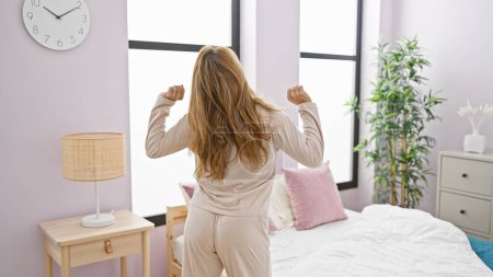 Photo for Woman stretching morning bedroom comfortable pajamas calm window - Royalty Free Image