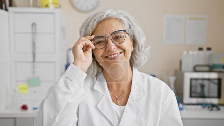 Photo for Mature woman scientist smiling confidently in a laboratory, showcasing professionalism and expertise. - Royalty Free Image