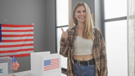 Mujer joven sonriente dando pulgares arriba en un centro electoral de EE.UU. con banderas americanas