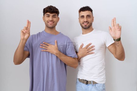 Foto de Homosexual pareja gay de pie sobre blanco fondo sonriendo jura con la mano en el pecho y los dedos hacia arriba, haciendo una promesa de lealtad juramento - Imagen libre de derechos