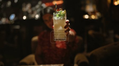 Cheerful, beautiful hispanic woman enjoying a tropical cocktail drink in a lively nightclub, embodying the essence of fun-filled nightlife.