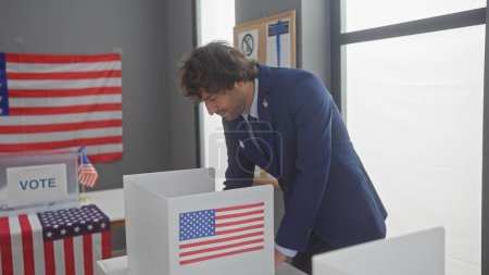 Schöner hispanischer Mann im Anzug bei der Stimmabgabe in einem amerikanischen Wahlzentrum, mit uns Fahnen