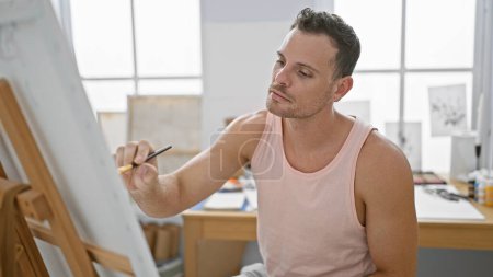 Téléchargez les photos : Peinture d'homme concentrée sur toile dans un cadre studio lumineux et créatif - en image libre de droit