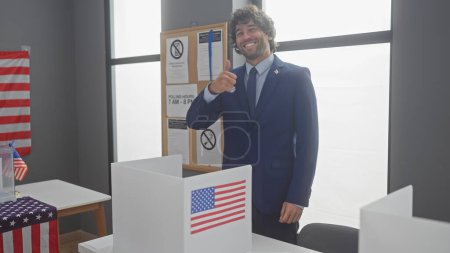 Lächelnder Mann mit Bart im Anzug gibt Daumen hoch vor amerikanischem Wahllokal mit Fahne