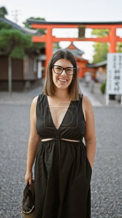 Fröhliche hispanische Frau posiert mit selbstbewusstem Lächeln am traditionellen Yasaka-Tempel, Kyoto. schöne brünette in brille, ausdruck unbeschwertes glück und lässig und doch erfolgreich stil in japan.