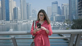 Brunette woman in red uses smartphone against dubai marina skyline backdrop, embodying luxury, travel, and modernity. Stickers #710168214
