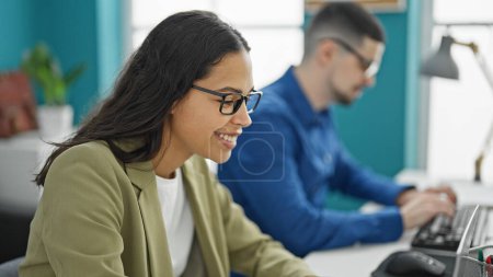 Photo for Cheerful workplace teamwork, two smiling man and woman workers confidently tackling tech tasks, working together online on computer at the office. - Royalty Free Image