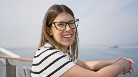 Foto de Mujer joven sonriente con gafas disfrutando de sus vacaciones en crucero en un día soleado en el mar. - Imagen libre de derechos