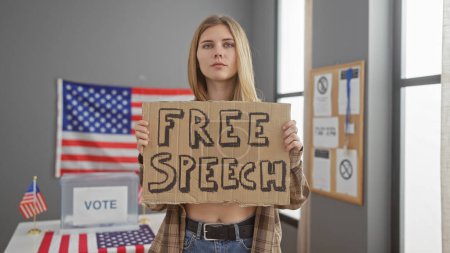 Mujer caucásica sosteniendo letrero marcado 'libertad de expresión' frente a bandera americana en el centro de votación