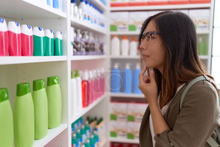 Photo for Young asian woman customer looking shelving at pharmacy - Royalty Free Image