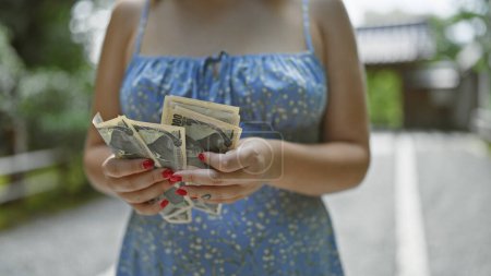 Téléchargez les photos : Les mains de la jeune femme, occupée à compter les billets de banque yens dans les rues traditionnelles de kyoto, un caucasien plongé dans les banques et les finances japonaises - en image libre de droit