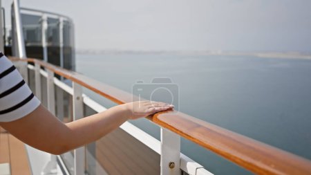 Téléchargez les photos : Femme profite de vacances de croisière paisibles, appuyé sur le pont ferroviaire du navire, regardant la mer. - en image libre de droit